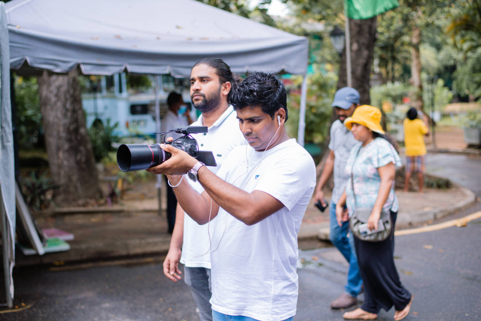 A man stands in front of a tent, holding a camera.