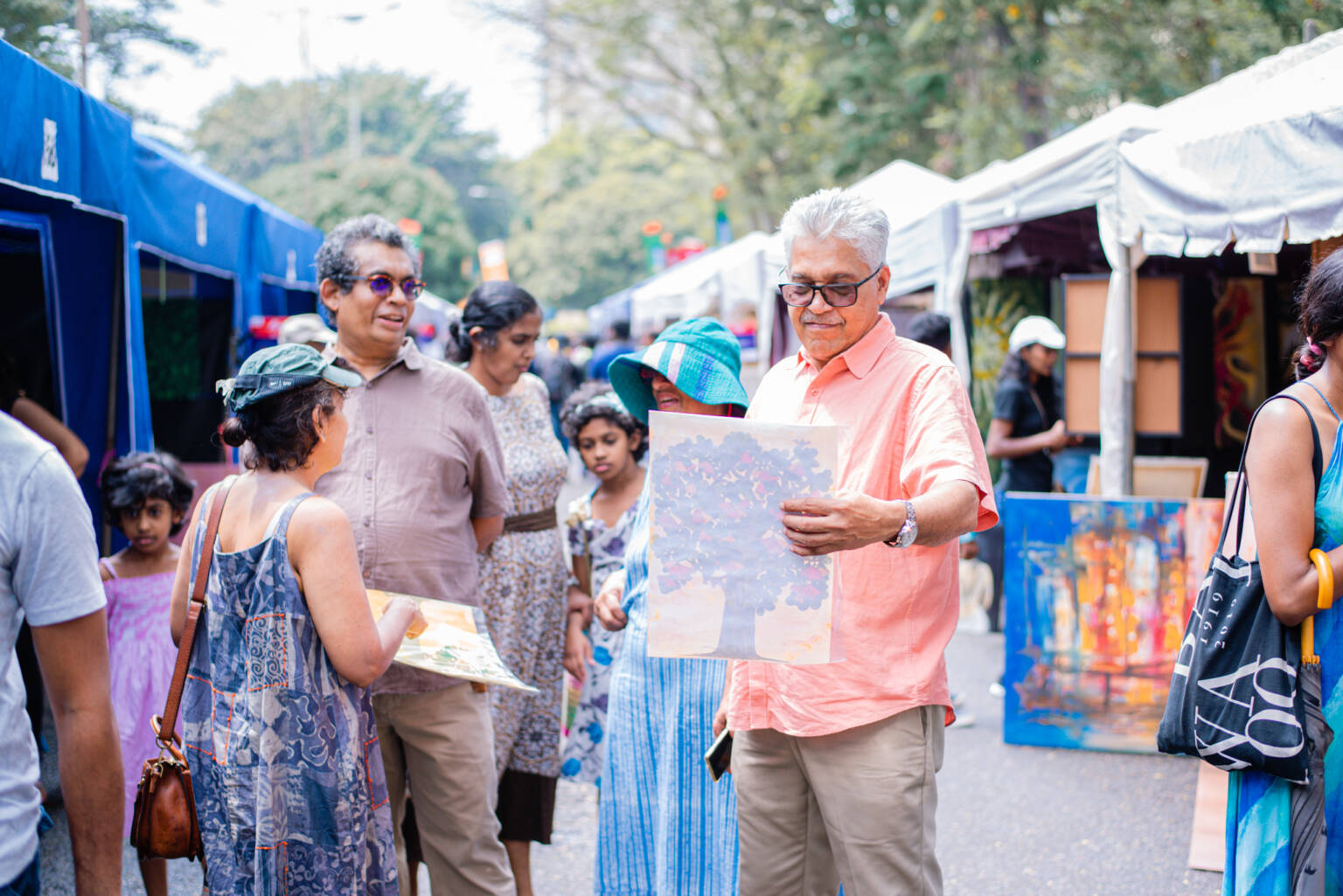 A man examines a picture while standing at an outdoor market.