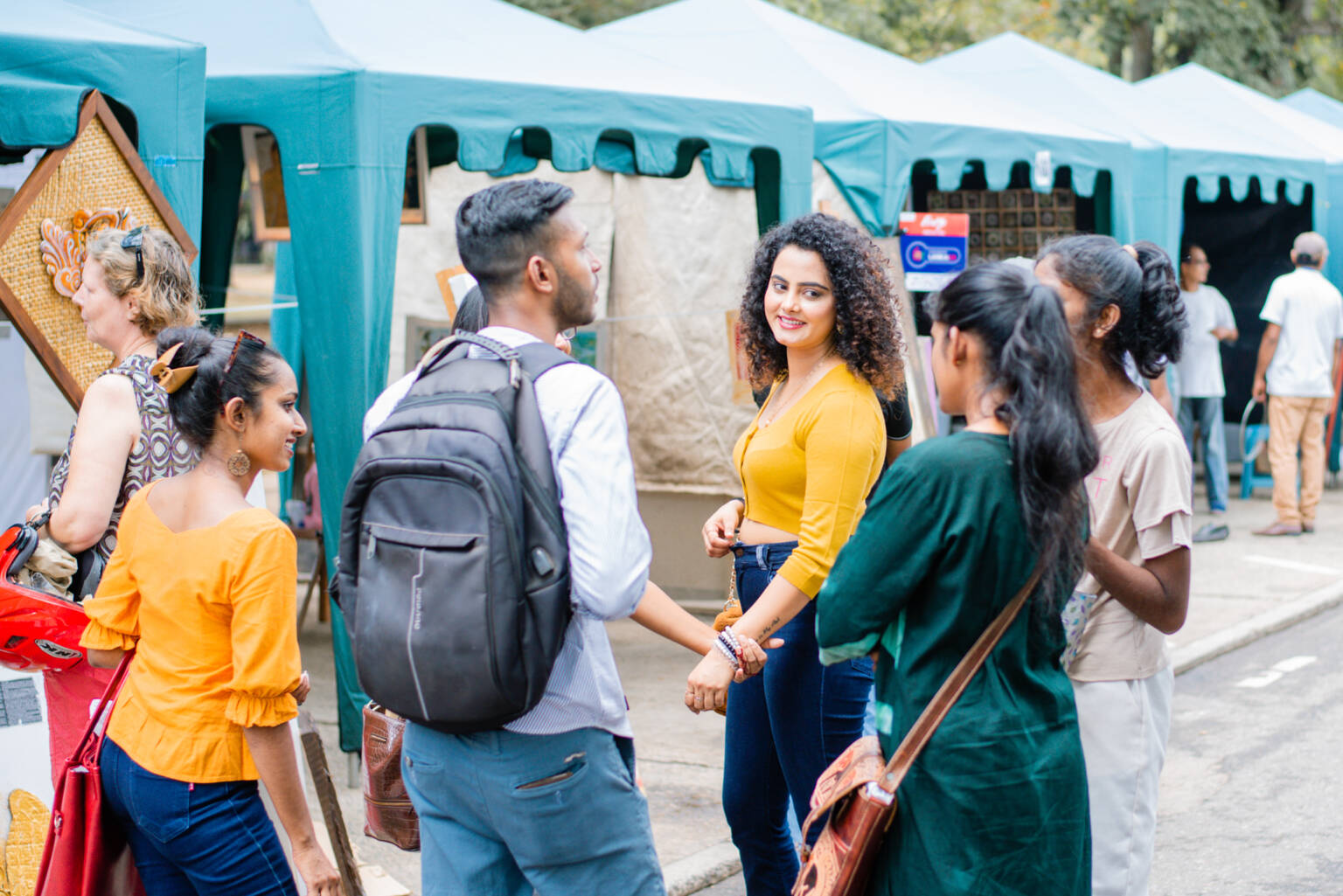 A man poses for a photo in front of a tent, standing beside a woman, both smiling and enjoying the outdoor setting.