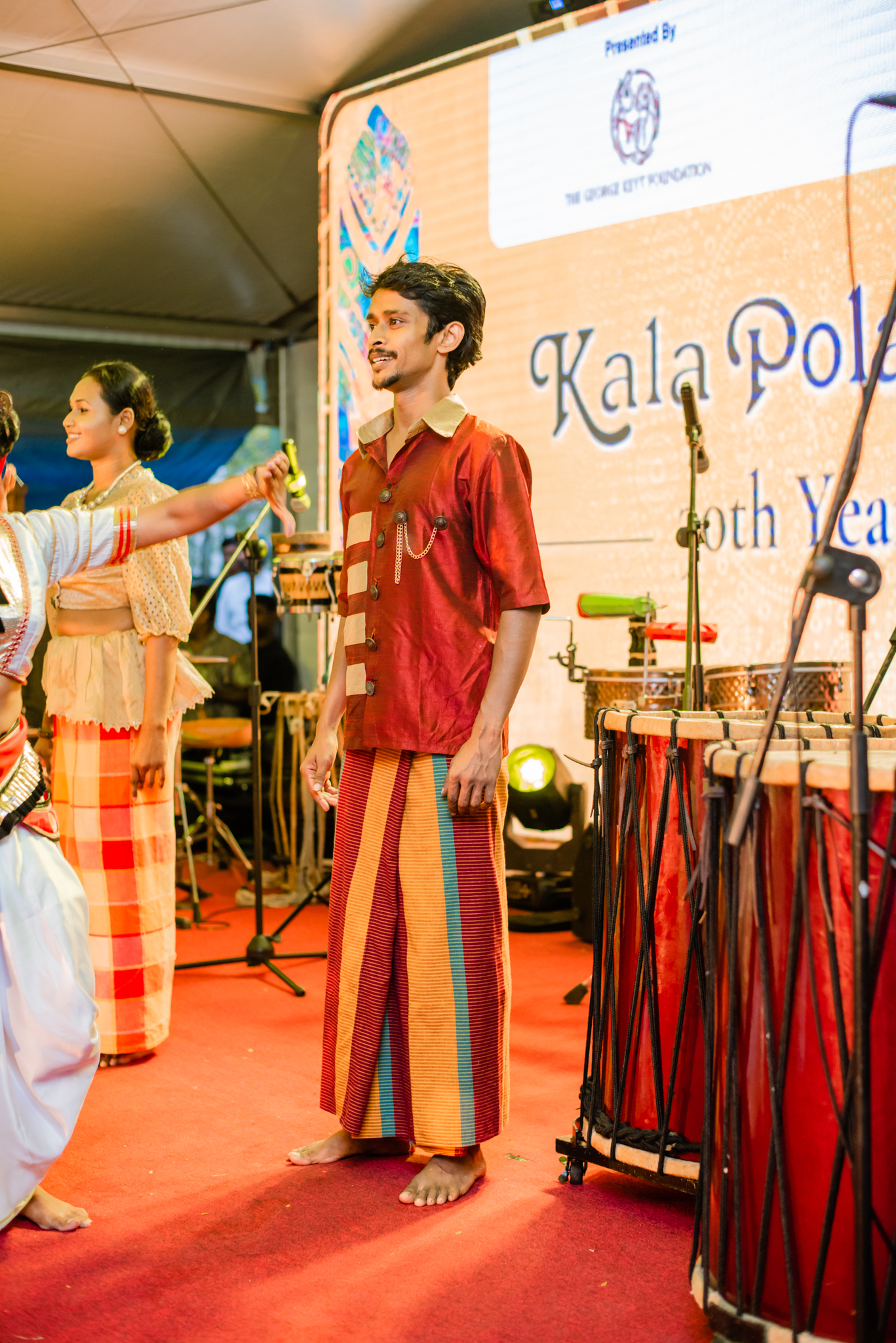 Women dressed in vibrant traditional costumes perform on stage, celebrating their cultural heritage through dance and music.